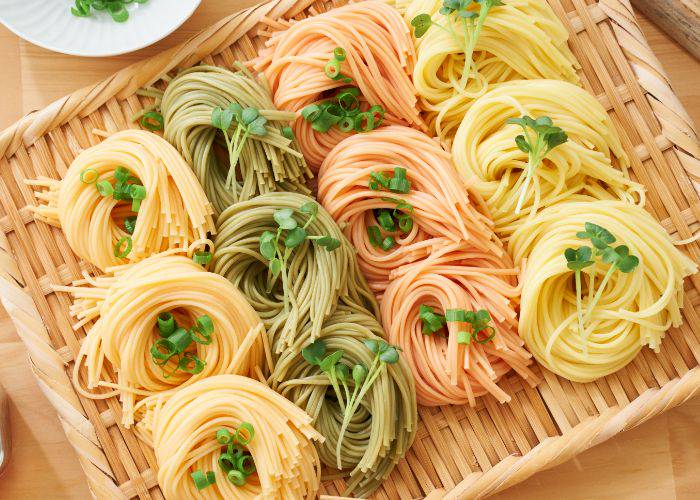Colorful somen noodles on a bamboo tray, curled into bundles and separated by color.